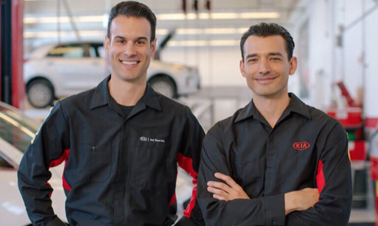 Two Kia technicians smiling in the shop