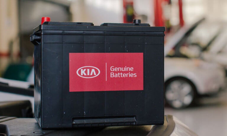 A Kia car battery on a table in the shop